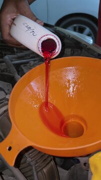 Close-up of engine oil being poured through a wide funnel into a vehicle