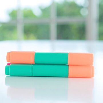 Two colorful office highlighters resting on a white table.