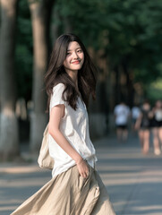 Obraz premium Young woman long hair white shirt beige skirt outdoor summer smiling walking tree lined path sunlight