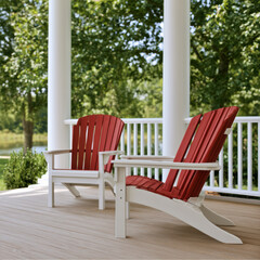 Fototapeta premium Red Adirondack chairs on wooden porch with white railing and columns, surrounded by green trees, peaceful outdoor seating area