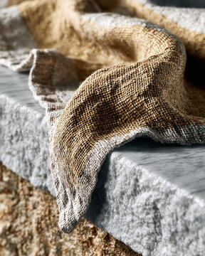 Natural linen fabric draped over rough stone edge close up