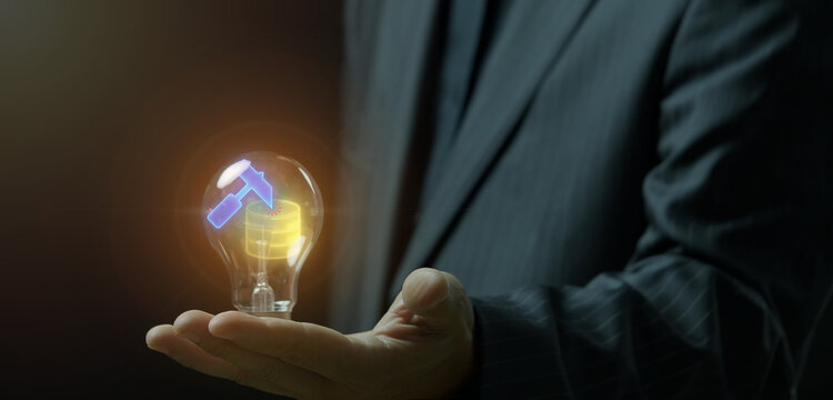 Close-up shot of hand holding glowing lightbulb containing hammer tool and database server icons. Data mining innovation idea, big data extraction, and deep data analytics discovery concept.
