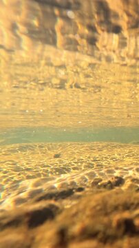 Sunlight Filtering Through Clear River Water Over Sandy Riverbed