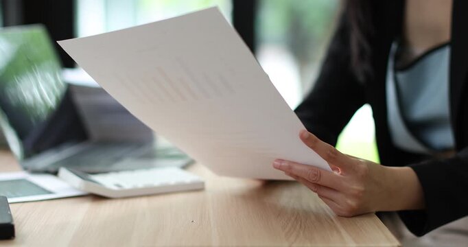 Businesswoman analyzing financial reports and working on laptop in modern office, managing business data
