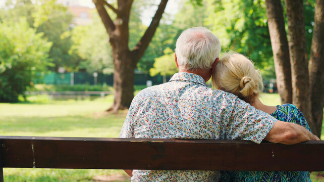Elderly couple enjoying a peaceful moment together on a park bench, embracing nature's tranquility