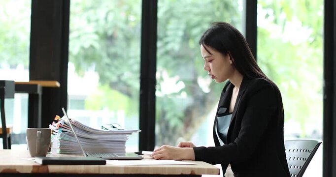 Young businesswoman analyzing financial documents and data, managing budget planning in a modern office