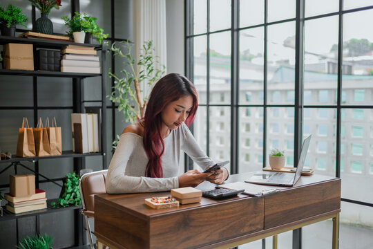 Woman checking ecommerce store with smartphone for online sales customer orders and business management.