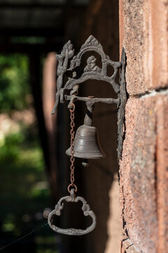 Vintage cast iron doorbell with small bell and chain. Antique metal doorbell with small decorative bell and pull chain mounted on brick wall, closeup
