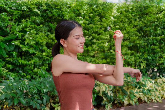 Asian Gen Z woman stretching shoulders representing wellness self care flexibility and active healthy lifestyle.