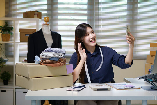 Young Asian Woman Fashion Entrepreneur Taking Selfie with Clothes for Online Store Social Media