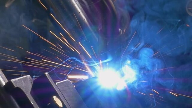 Watch as an advanced argon welding robot skillfully fuses metal pipes in a dynamic industrial setting. Sparks fly and bright blue arcs illuminate the scene, showcasing precision in action.