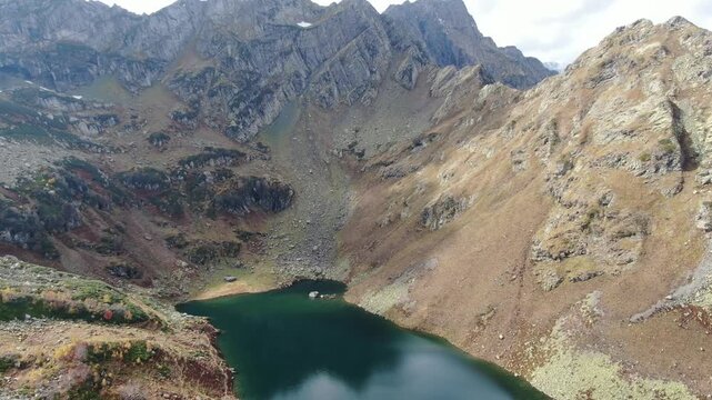 Aerial view of the pristine alpine Lake Mzy nestled in a dramatic high-altitude rocky cirque in the mountains of Abkhazia.