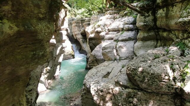 Scenic view of the crystal-clear Khosta River flowing through the deep white rock canyon and lush green forest in Sochi, Russia.