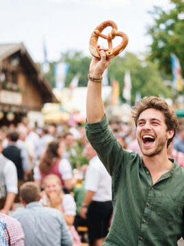 German folk music culture oktoberfest joyful man holding pretzel at festival