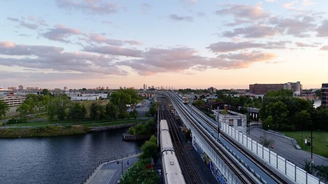 Passenger train passing through Griffintown, Montreal, Quebec, Canada at sunset with modern skyline. g.