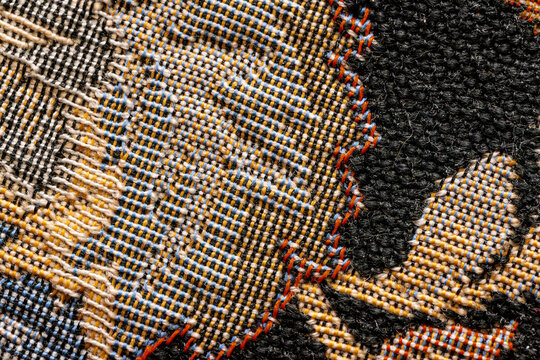 Macro texture of embroidered tapestry fabric with colorful thread patterns.