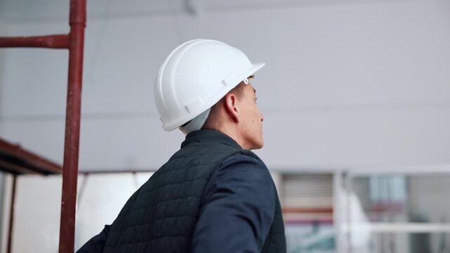 Thinking, helmet and back of man in building for inspection, safety compliance and planning at site. Architecture, construction person and ppe for renovation, remodeling and property evaluation