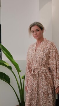 Elegant woman wearing luxury kimono robe in modern tropical home.
