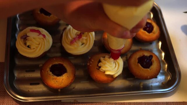 A pastry chef skillfully decorates cupcakes with smooth white frosting using a piping bag, creating an exquisite dessert in a bustling professional kitchen filled with mouth-watering aromas. Slow moti