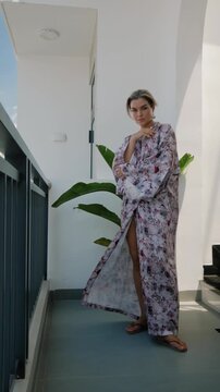 Elegant woman wearing luxury kimono robe in modern tropical home.
