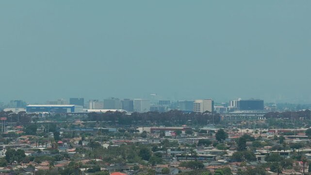 Telephoto aerial tracking shot of a plane landing at Los Angeles International Airport on a hazy day as seen from Hawthorne, California. 4K