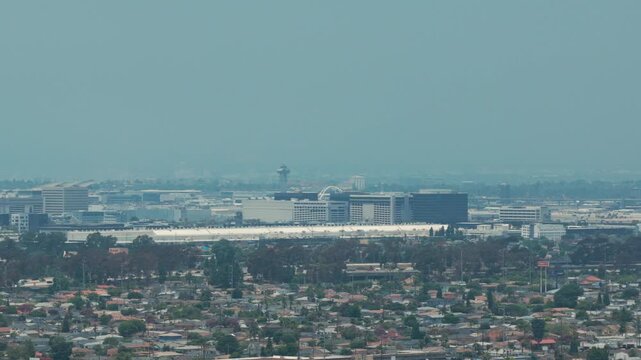 Aerial telephoto panning shot of Los Angeles International Airport in the distance from Hawthorne, California during hazy conditions. 4K