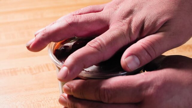 Close up cooking footage showing adding plastic lid to container for chamoy sauce during a homemade chamoy sauce recipe prepared from scratch