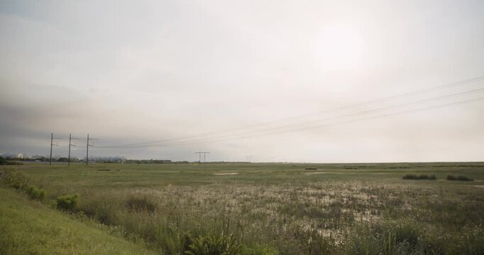 4K footage, Wide Pan across Florida Everglades in Broward County. Lands on multiple wildfire hotspots and smoke burning across sawgrass marshes. Powerlines and dirt road in foreground.