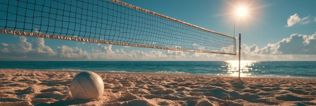 A volleyball rests on the sandy beach near a net with the sun shining brightly over the ocean horizon.