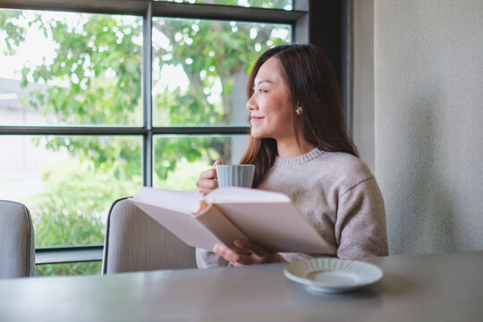 Portrait image of a woman reading a book and drinking coffee
