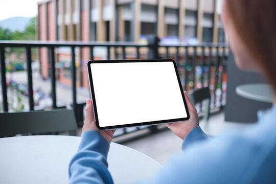 Mockup image of a woman holding digital tablet with blank white desktop screen in cafe