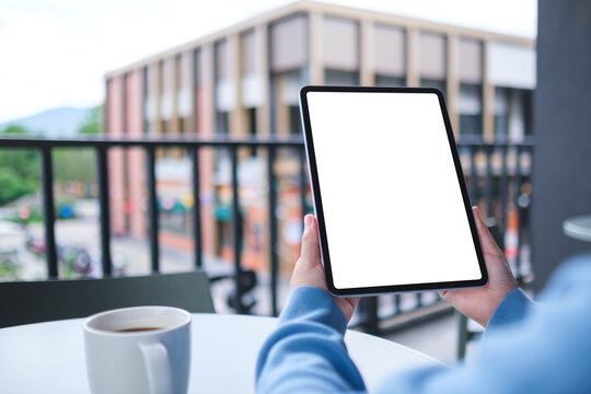 Mockup image of a woman holding digital tablet with blank white desktop screen in cafe