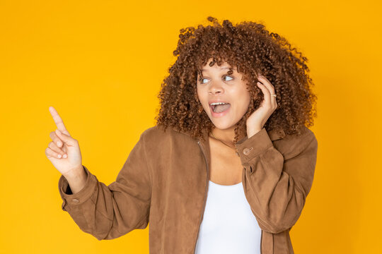 isolated young woman pointing in surprise, copy-space