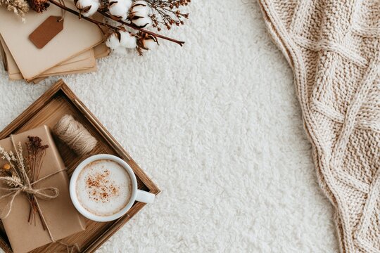 Autumn flat lay with a cozy knitted blanket coffee gift and cotton on white desk