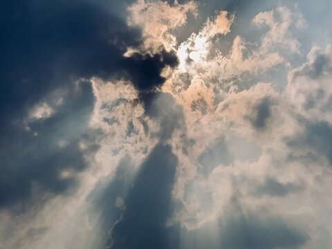 Bright sunlight filters through dense cloud formations above Jakarta, Indonesia, creating visible rays and atmospheric contrast. Suitable for weather, environmental and inspirational visual concepts.