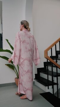 Elegant woman wearing luxury kimono robe in modern tropical home.