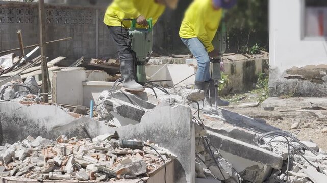 view to worker while demolishing solid concrete jutting destroy wall with concrete demolition hammer, Rotary Hammer in sunny day prepare for construction site