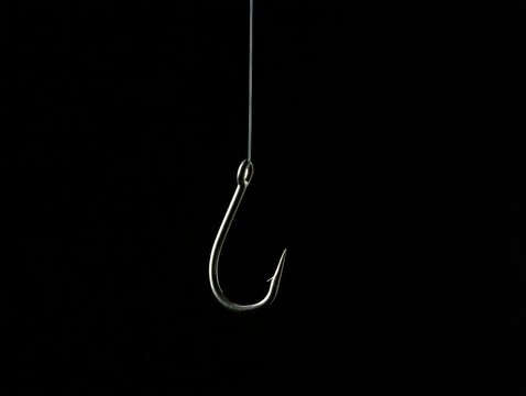 A sharp metal fishing hook hanging from a fishing line against a black background