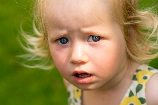 Serious Blonde Toddler Looking Aside in Summer Park