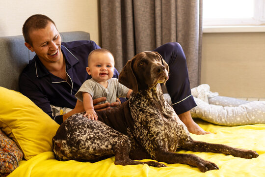 Smiling Father And Baby Son Beside German Shorthaired Pointer