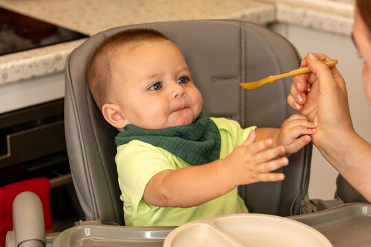Baby Boy Reaches For Spoon During Kitchen Mealtime
