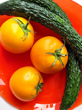 Fresh Yellow Tomatoes with Cucumber on Red Plate