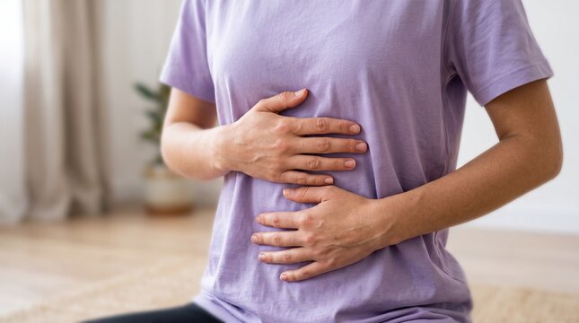 Woman holding hands on abdomen during belly breathing exercise at home.
