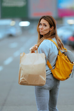 Stressed Confused Woman Wearing Backpack Holding Brown Paper Shopping Bag. Anxious lost female customer looks puzzled carrying heavy groceries 