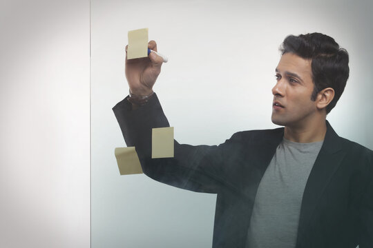 Businessman writing on adhesive notes in office