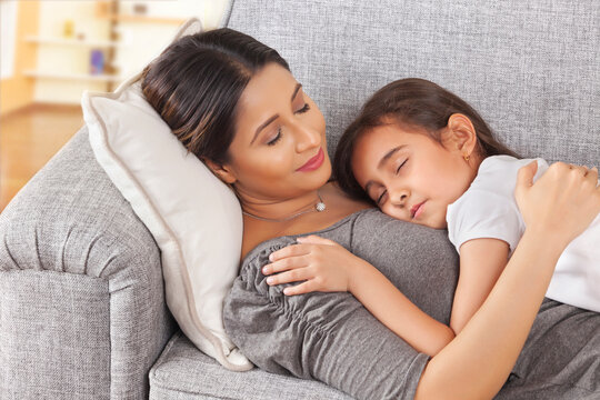 Mother and young daughter sleeping together on couch