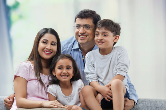 Close-up of family with two children sitting on sofa together