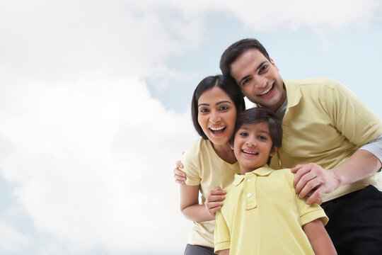 Portrait of a happy family looking at the camera against sky and clouds