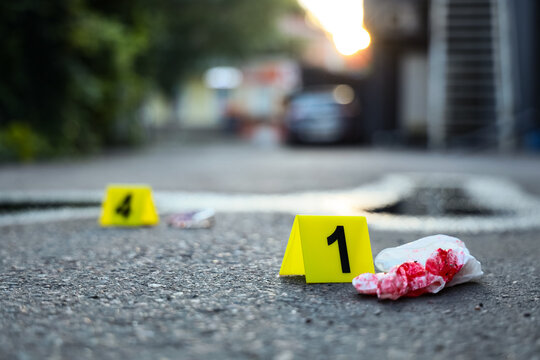 Crime scene evidence marker number one next to bloody tissue on asphalt, Forensic investigation concept, Forensic analysis and legal proceedings are implied by the presence of collected evidence