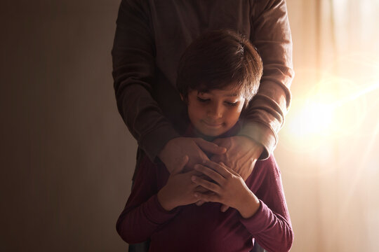 Boy holding his father hands standing together nearby the window 